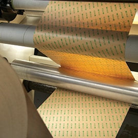 Lær om trinn 3, identifisere prosesstrinn, i 3M ASPEC-metoden. Bilde av rull med limoverføringstape i produksjonsprosessen.